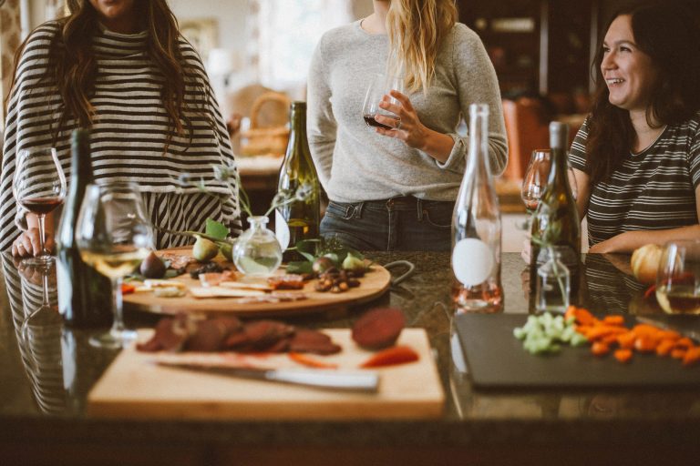 Group of people enjoying a food platter with various drinks on a table in a casual setting.