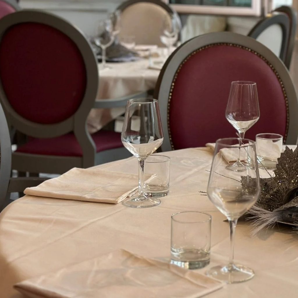 A dining table set with wine glasses, water glasses, and neatly arranged napkins.