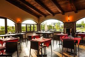 Interior view of a dining area featuring tables with red tablecloths and chairs.
